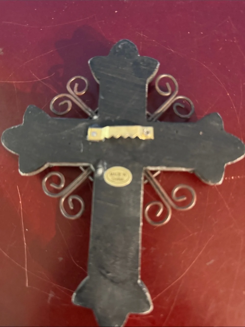 Silver-tone wall cross features a central turquoise stone and scrollwork detail